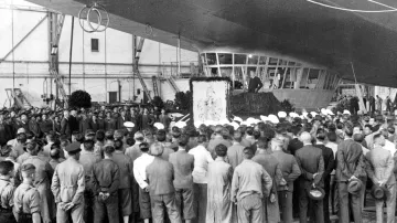 Kapitánem prvního letu byl Hugo Eckener. Na snímku u rodinného erbu před kokpitem posádky slavnostně představuje novou vzducholoď LZ 130 'Graf Zeppelin II' v hale Friedrichshafen 14. září 1938.