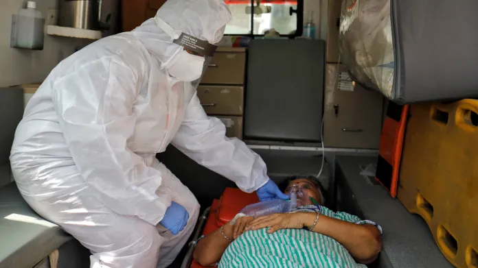 Indický zdravotník podává nemocné ženě kyslík