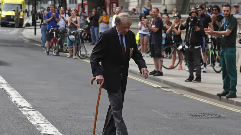 Lidé tleskají válečnému veteránovi po dvou minutách ticha, které proběhly pro připomenutí konce války ve Whitehall v Londýně