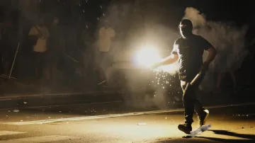 Příznivci srbského prezidenta Aleksandara Vučiče házejí světlice na protivládní demonstranty během protestu před kanceláří Srbské pokrokové strany v Bělehradě 14. srpna 2025