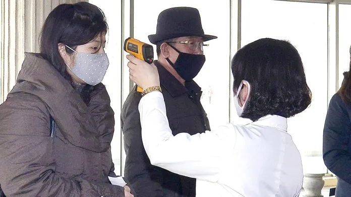 Zdravotníci měří lidem v Pchjongjangu teplotu