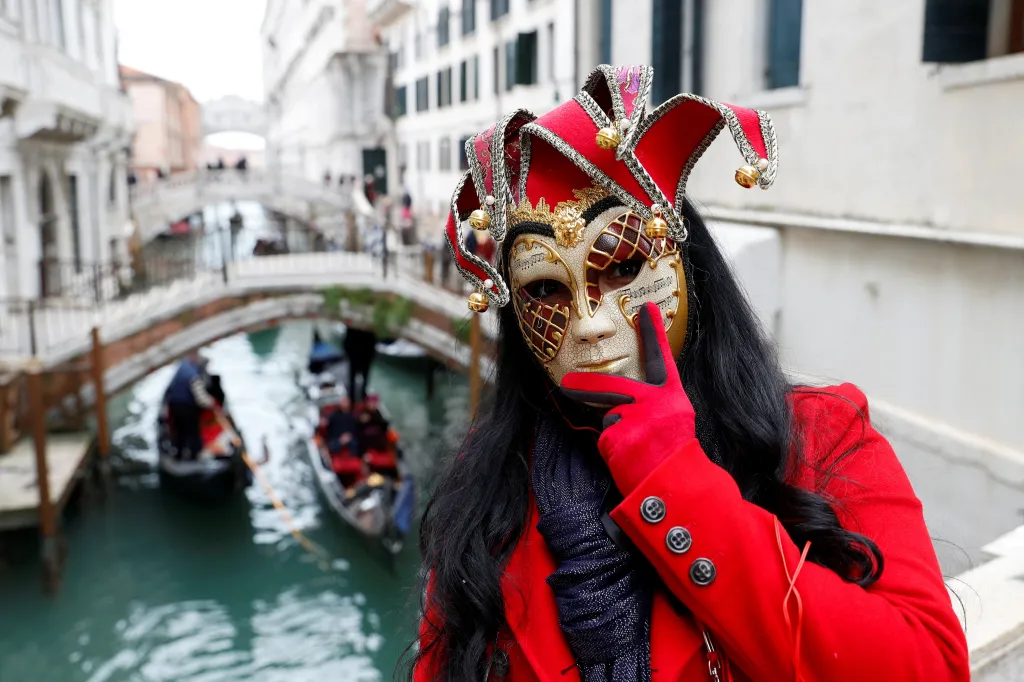 Lidé oslavují podél benátských kanálů, kde proplouvají ozdobené gondoly
