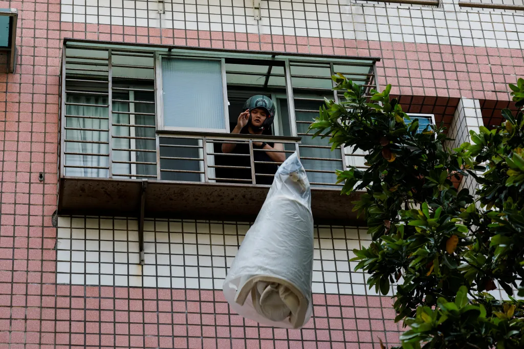 Obyvatel poškozené budovy vyhazuje své věci z okna