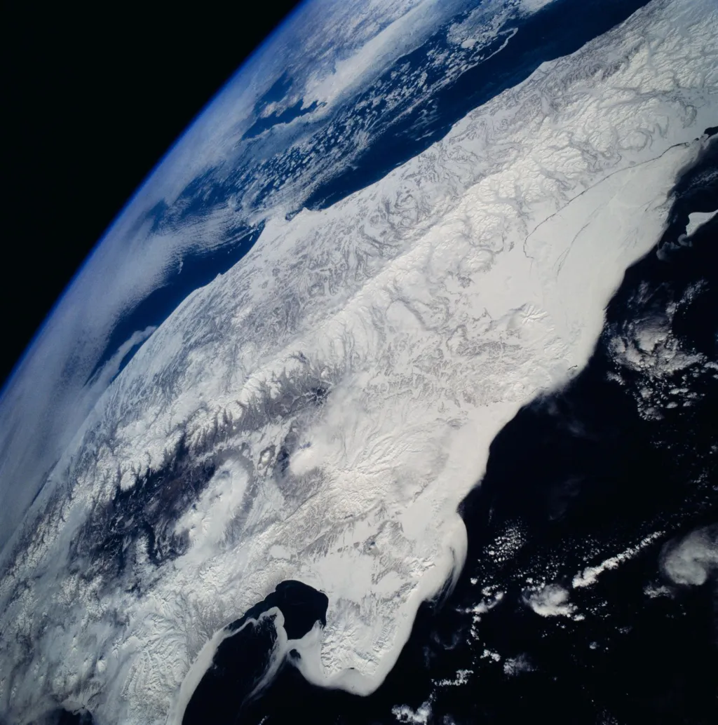 Led, sníh a shluk aktivních vulkánů uprostřed Kamčatky na snímku z vesmíru