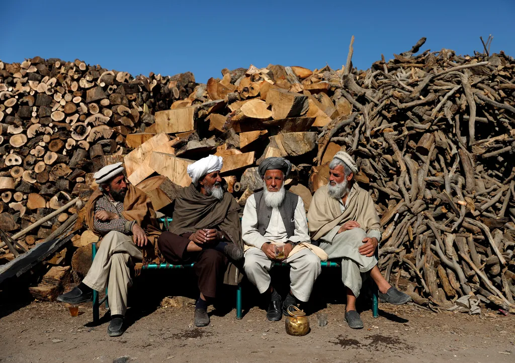 Afghánští mužové sedí před svým stánkem s palivovým dřívím v Kábulu