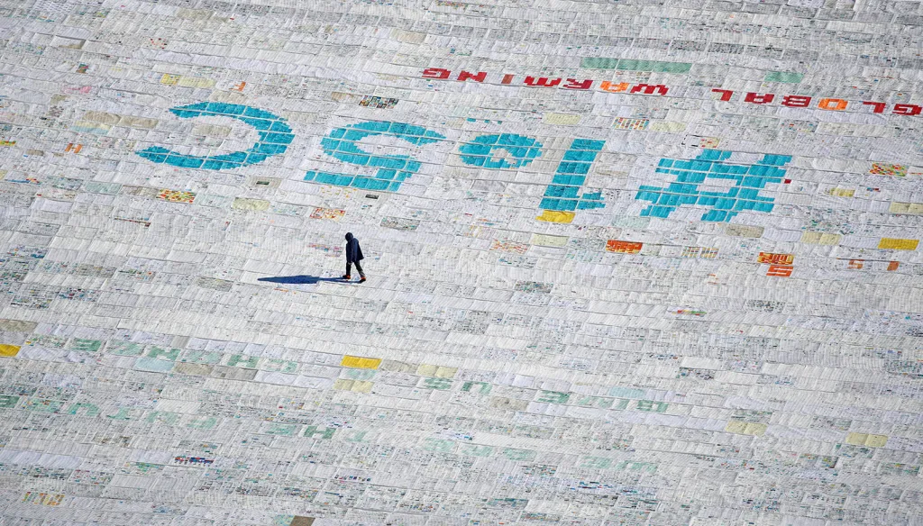 Muž procházející se po sto tisících pohlednic proti globálnímu oteplování. Vzkazy napsali mladí lidé z celého světa ve snaze prolomit rekord z Guinessovy knihy o největší pohlednici na největším evropském ledovci Aletschgletscher ve švýcarských Alpách.
