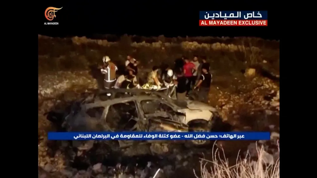 Záběry televize Al-Mayadeen ukazují záchranné týmy pracující u ohořelého vozidla