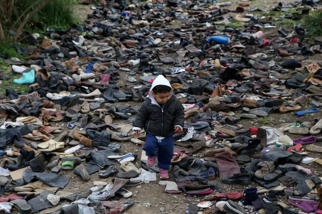 Malý chlapec prochází cestou plnou bot v táboře pro migranty. Ostrov Lesbos v Řecku