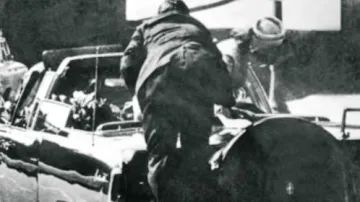 Agent Clint Hill skáče na Kennedyho limuzínu