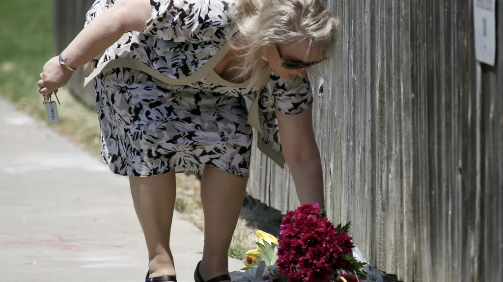 Žena kladoucí květiny k místu vraždy Dr. Tillera