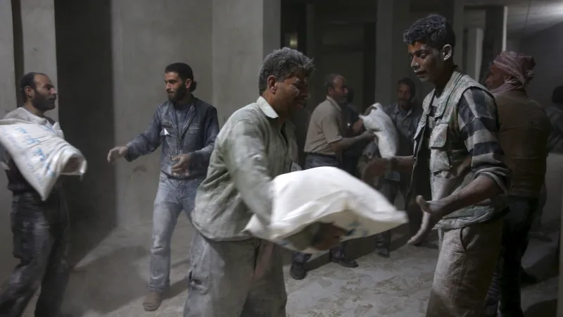 Muži vykládají mouku z konvoje Mezinárodního červeného kříže v damašském předměstí