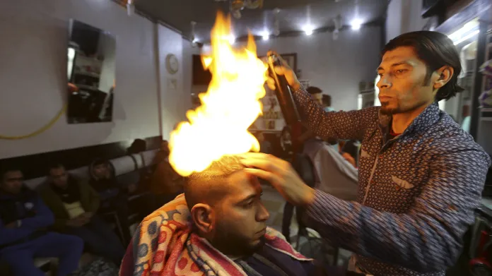 Palestinský holič Ramadan Odwan používá oheň při práci s vlasy svých zákazníků ve svém salonu ve městě Rafah v pásmu Gazy.