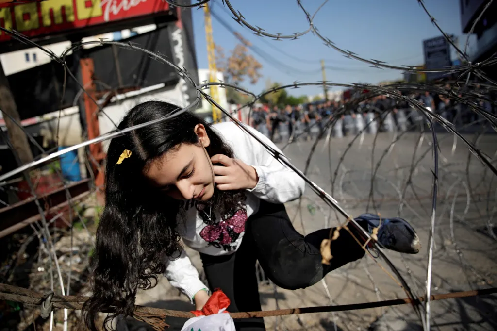 Děvče prolézá zábrany u amerického velvyslanectví v Libanonu během protestů a policejní blokády
