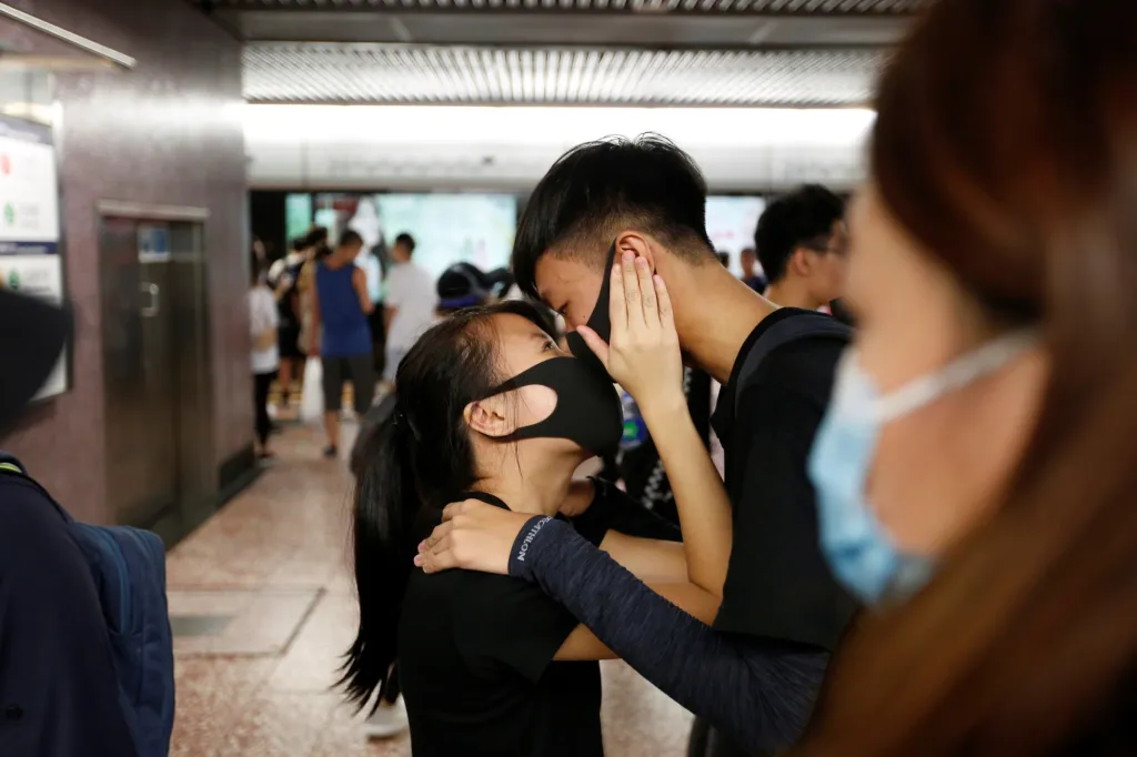 Protestující pár se objímá ve stanici hongkongského metra poté, co se demonstranti museli přeskupit před policejním zásahu slzným plynem (11. srpna 2019)