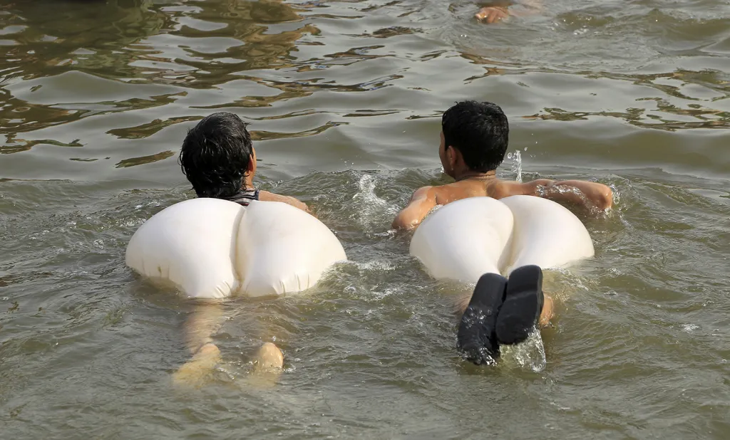 Dva pákistánští chlapci v plavkách se koupou v řece během letního dne v Islamabadu.