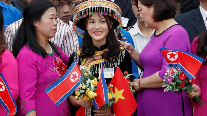 Žena s vlaječkami KLDR a Vietnamu čeká na severokorejského vůdce Kim Čong-una na nádraží ve vietnamském Dong Dangu