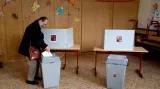 Volič vhazuje obálku do volební urny v Praze