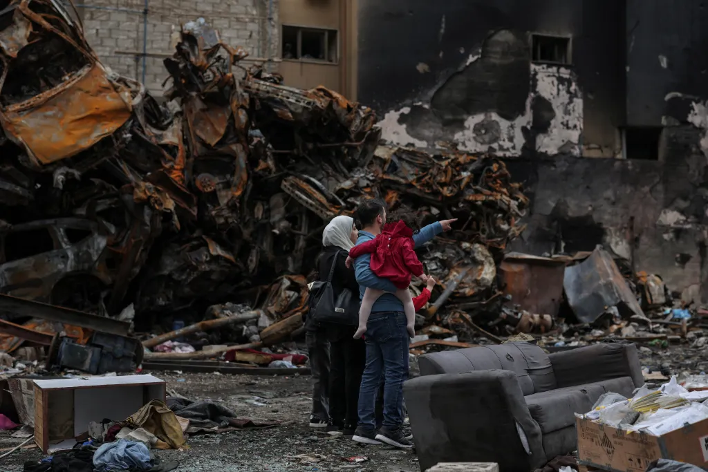 Rodina, která žije ve stejné čtvrti, si prohlíží dům zničený během izraelského útoku